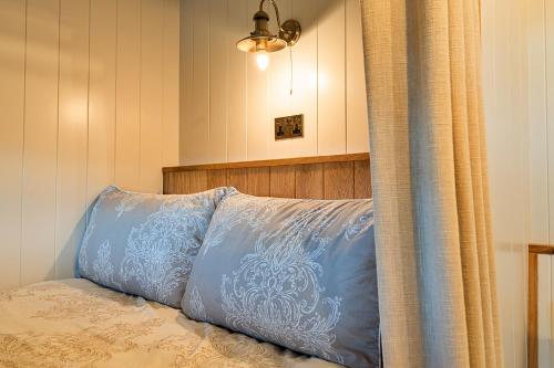 a blue pillow sitting on top of a bed at Finest Retreats - The Shepherd's Hut at Northcombe Farm in Beaworthy