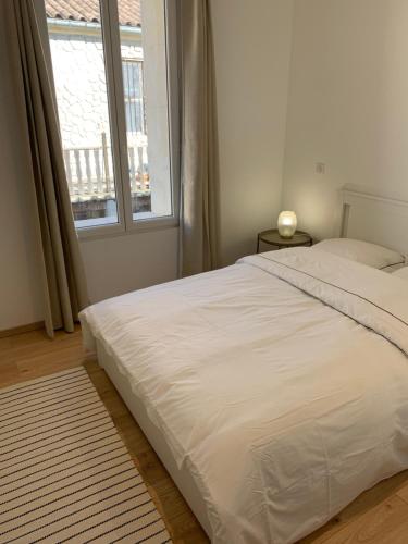 - un lit blanc dans une chambre avec fenêtre dans l'établissement Arles : maison de ville a deux pas de tour Luma, à Arles