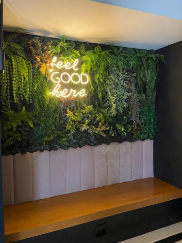 a green wall with a sign that reads good karma at Cegil Hotel Boulevard in Resende