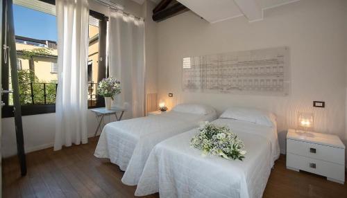 a white bedroom with a bed with flowers on it at LT - Room's Bed & Living in Monza