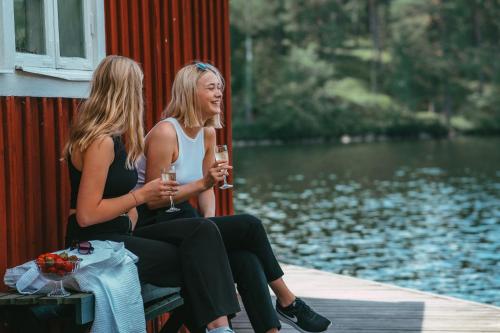 two women sitting on a dock with glasses of wine at Fredensborgs Herrgård in Vimmerby