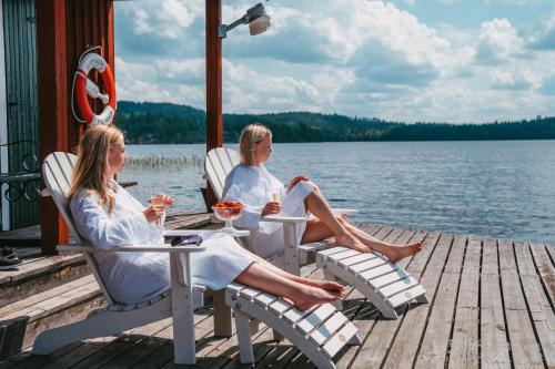 two women sitting on a dock on a lake at Fredensborgs Herrgård in Vimmerby
