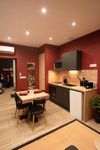 a kitchen with a table and a kitchen with red walls at Capsule Japon - Jacuzzi - Netflix & Ecran Cinéma - Xbox in Saint-Léger