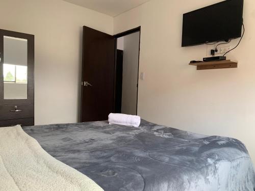 1 dormitorio con 1 cama grande y TV de pantalla plana en la pared en Apartamento cerca del CC Titan Plaza, en Bogotá