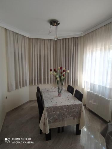 a dining room table with two chairs and a vase of flowers at VILLA ALKMINI NEAR THE AIRPORT in Vravrona