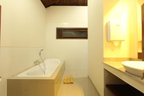 La salle de bains blanche est pourvue d'une baignoire et d'un lavabo. dans l'établissement Mahanadewi Villa, à Ubud
