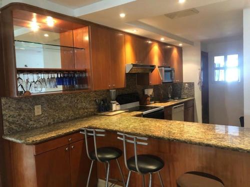 a kitchen with wooden cabinets and bar stools at Mayan Vidanta departamento 2 recámaras CON SERVICIO DE PLAYA in Acapulco