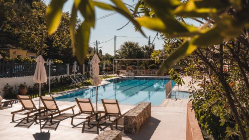 a pool with chairs and umbrellas in front of a resort at Dominoes Corfu in Ýpsos