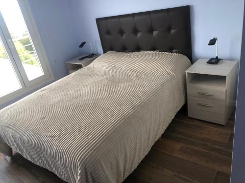 um quarto com uma cama grande e uma cabeceira preta em Mirador del Kaiken em Ushuaia