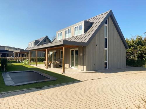 een huis met een gambrel dak en een patio bij luxe Villa Maroma Regal aan Veerse meer met 4 Ebikes GasBBQ & EV laadpaal in Kamperland