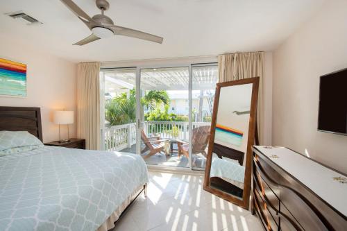 a bedroom with a bed and a television and a balcony at Beach Living at Island Pine Villas BLAW in George Town