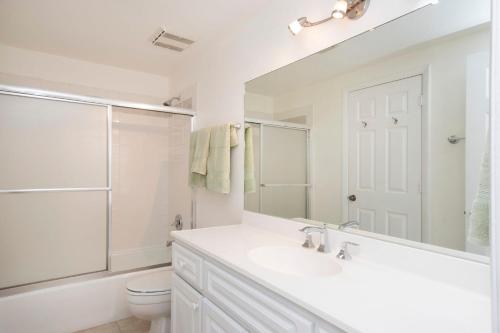 Baño blanco con lavabo y aseo en Dive into Sunsets at The Residences, en George Town