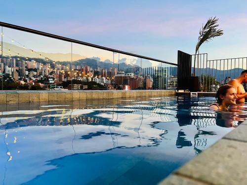 a couple in a swimming pool with a city skyline at Los Patios Hostel in Medellín