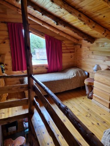 a bedroom in a log cabin with a bed and a window at Las Cuatro Lunas in Lago Meliquina