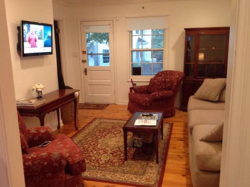 een woonkamer met een bank en stoelen en een tv bij Charming Cottage on a City Farm! in Lexington