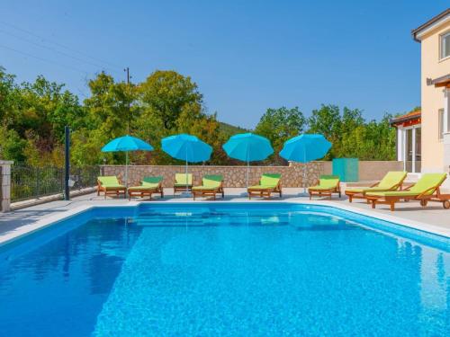 a swimming pool with chairs and blue umbrellas at Villa Secret Beauty with Heated Saltwater Pool in Imotski