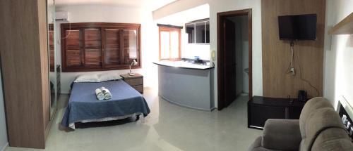 a small room with a bed and a kitchen at Flat ao lado do Shopping in Santa Cruz do Sul
