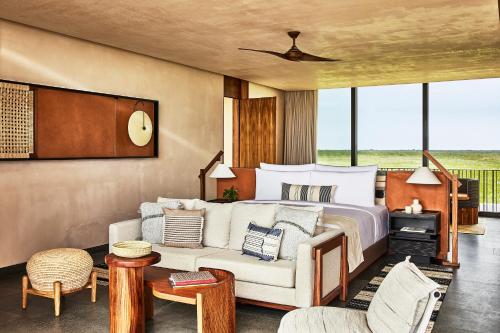 a bedroom with a bed and a couch at Etéreo, Auberge Collection in Playa del Carmen