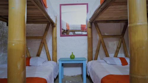 ボゴタにあるLima Limon Candelaria Hostelのベッド2台と青いテーブルが備わる客室です。