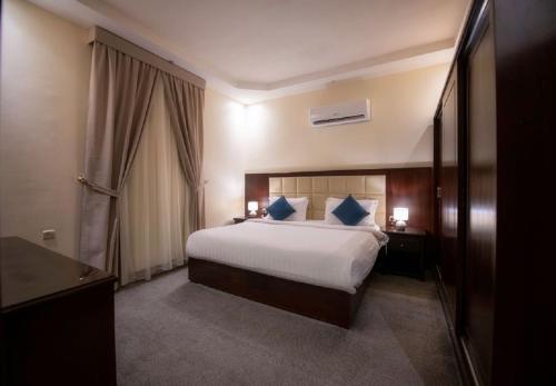 a hotel room with a bed with blue pillows at شقق ركن مدهال جازان للشقق المخدومة in Jazan