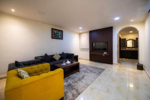 a living room with a yellow couch and a television at شقق ركن مدهال جازان للشقق المخدومة in Jazan