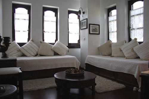 a living room with two beds and windows at Hotel Petrino in Makrinítsa