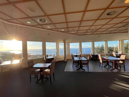 Un comedor con mesas y sillas y ventanas. en Stav Hotel, en Malvik