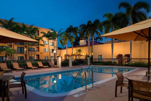 una piscina en un hotel con mesas y sombrillas en Sonesta Select Boca Raton Town Center, en Boca Raton