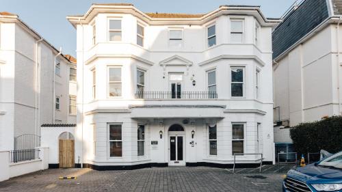 a white house with a car parked in front of it at Spacious 2 bedroom flat near beach and town centre in Bournemouth