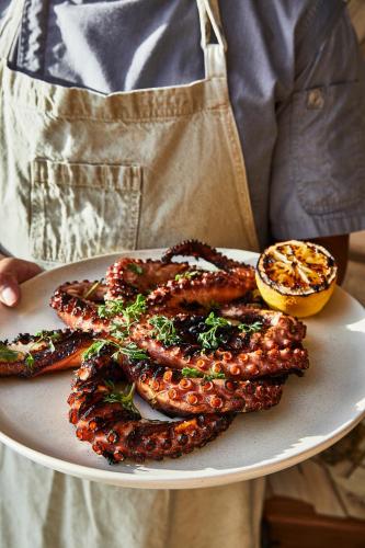 a person is holding a plate of food with tentacles at Etéreo, Auberge Collection in Playa del Carmen