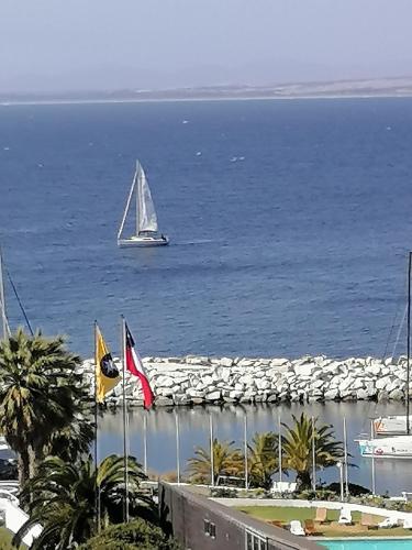 a sailboat in the water with a boat in the ocean at Depto Ambiente Privado con Vista al Mar in Concón