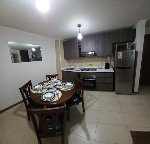 een keuken met een tafel en stoelen en een koelkast bij DEPARTAMENTO EDIFICIO AZUL I in Iquique