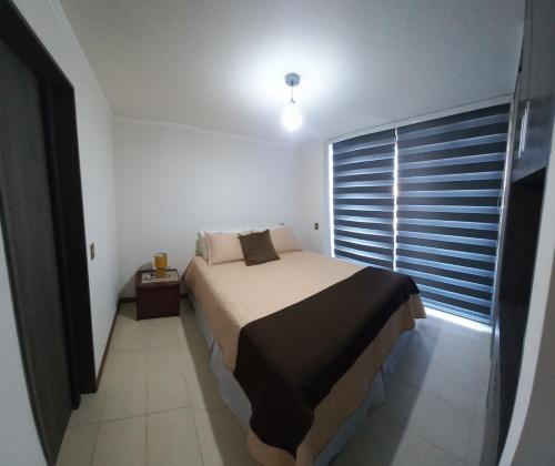 um quarto com uma cama e uma grande janela em DEPARTAMENTO EDIFICIO AZUL I em Iquique