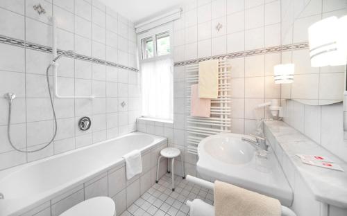 Baño blanco con bañera y lavamanos en Waldgasthof Wildbad, en Burgbernheim