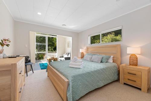 a bedroom with a bed and a desk and two windows at Francis Orchard Country Stay - Waipu Holiday Home in Waipu Cove