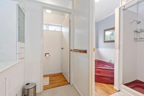 a bathroom with a door leading to a red tub at Francis Orchard Country Stay - Waipu Holiday Home in Waipu Cove