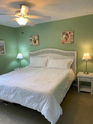 a bedroom with a white bed with green walls at True Blue Hideaway in Pawleys Island