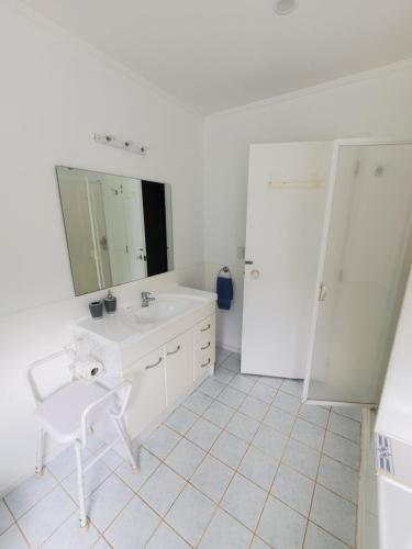 a white bathroom with a sink and a mirror at Quiet Waters in Ohaeawai