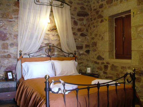 ein Schlafzimmer mit einem Bett in einer Steinmauer in der Unterkunft Xenonas Thalis in Skoutari