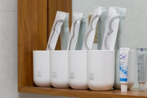 a group of white cups sitting on a shelf at Locals Apartment Inn 04 in Haikou