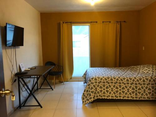 a bedroom with a bed and a desk and a window at Consulado Suites in Monterrey