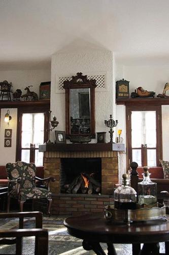 a living room with a fireplace and a table at Hotel Petrino in Makrinítsa