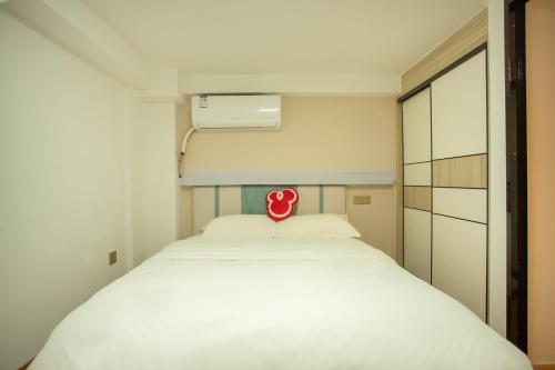 a small bedroom with a white bed with a red sign on it at Locals Apartment Place 44 in Zhanjiang