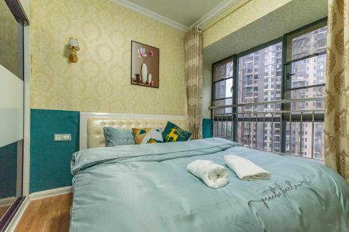 Un dormitorio con una cama azul con toallas. en Locals Apartment Inn 01, en Ganzhou