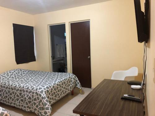 een slaapkamer met een bed, een tafel en een televisie bij Consulado Suites in Monterrey