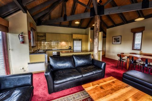 a living room with black leather furniture and a kitchen at Gundanora in Mount Hotham