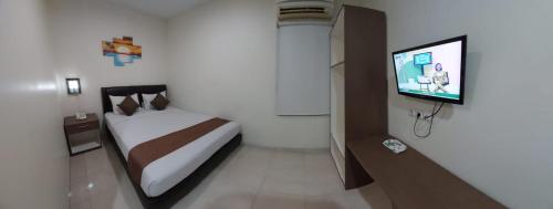 a bedroom with a bed and a flat screen tv at Grand Avira Hotel in Batu Merah