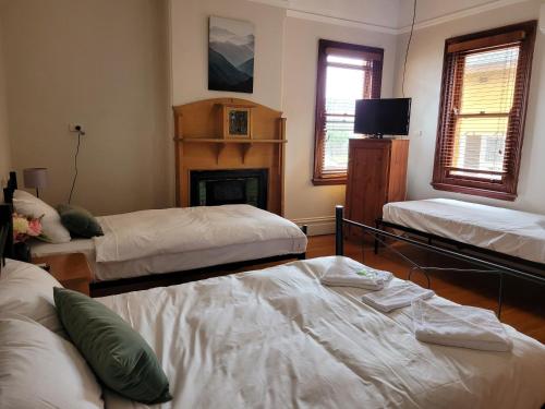 sala de estar con 2 camas y chimenea en Burwood Bed and Breakfast, en Sídney