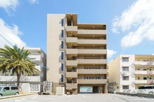 a tall building with a palm tree in front of it at Villa Awase 111 in Okinawa City