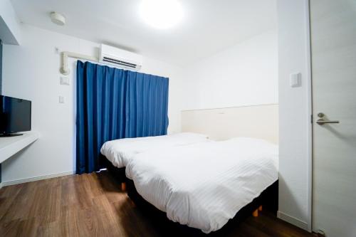 a bedroom with two beds and a blue curtain at Villa Awase 111 in Okinawa City